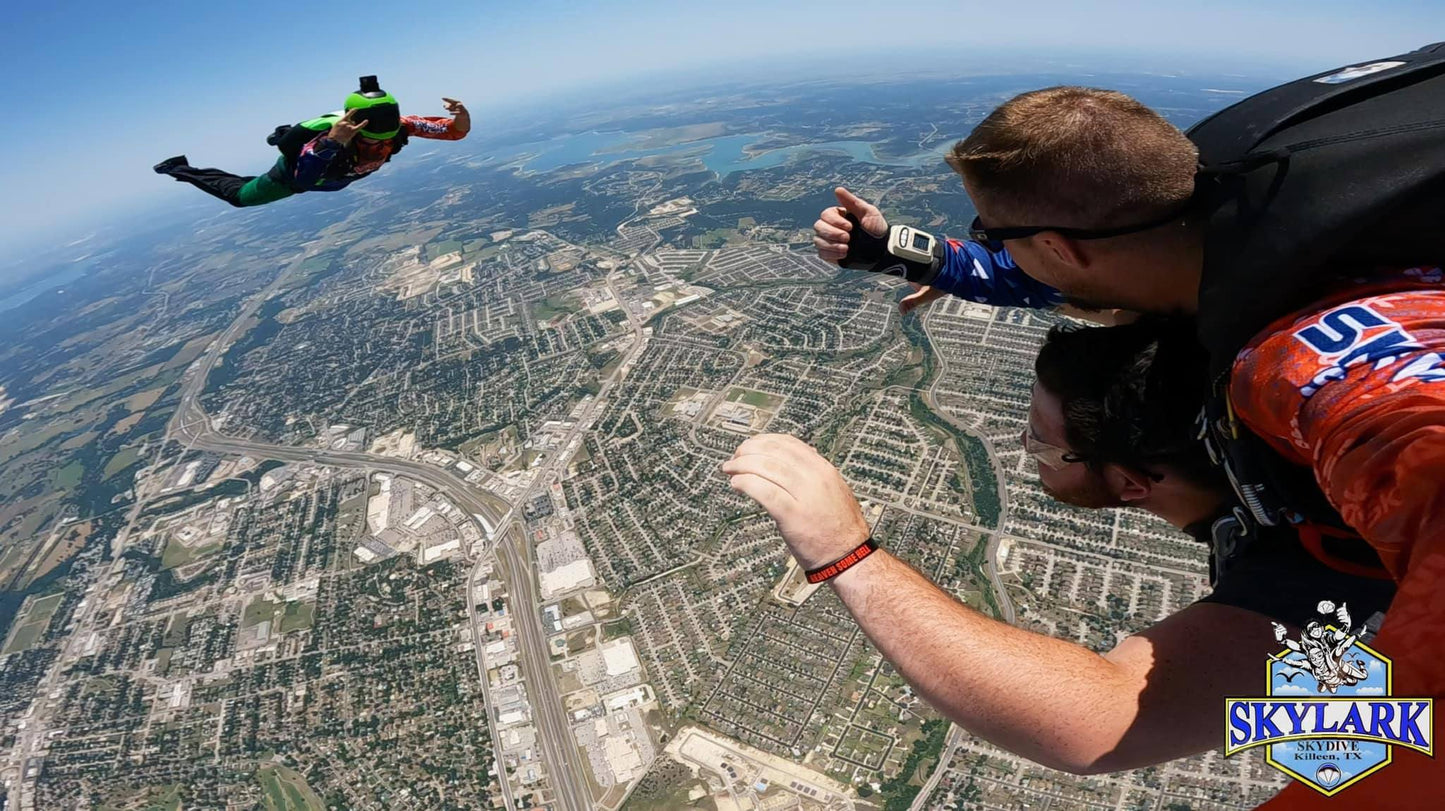 Tandem skydive with a videographer and a city and lake in the background